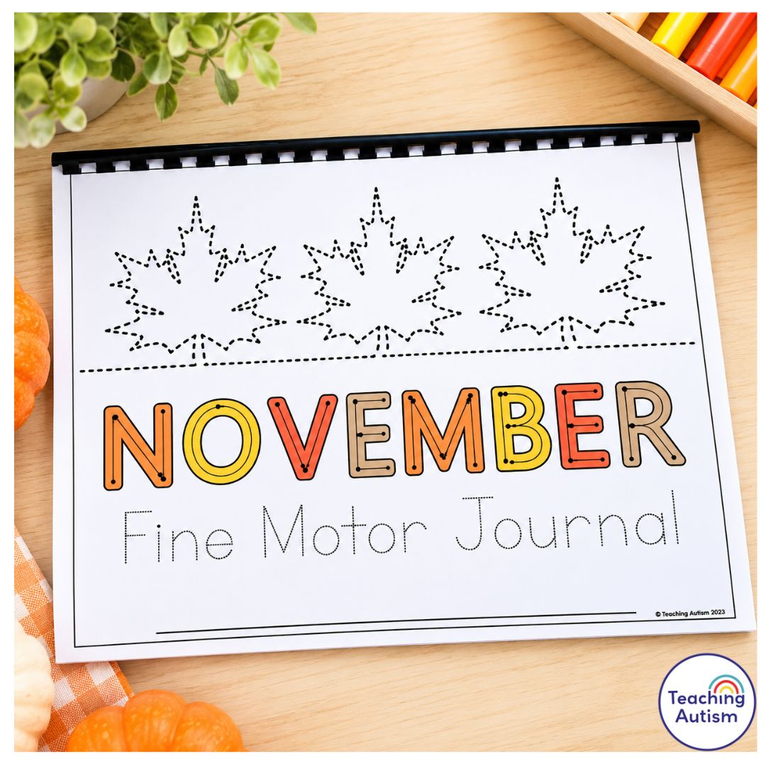 November Fine Motor Journal printable worksheet cover featuring fall leaf tracing activities, colorful November lettering, and spiral binding, displayed on a light wooden table with pumpkins and classroom supplies.